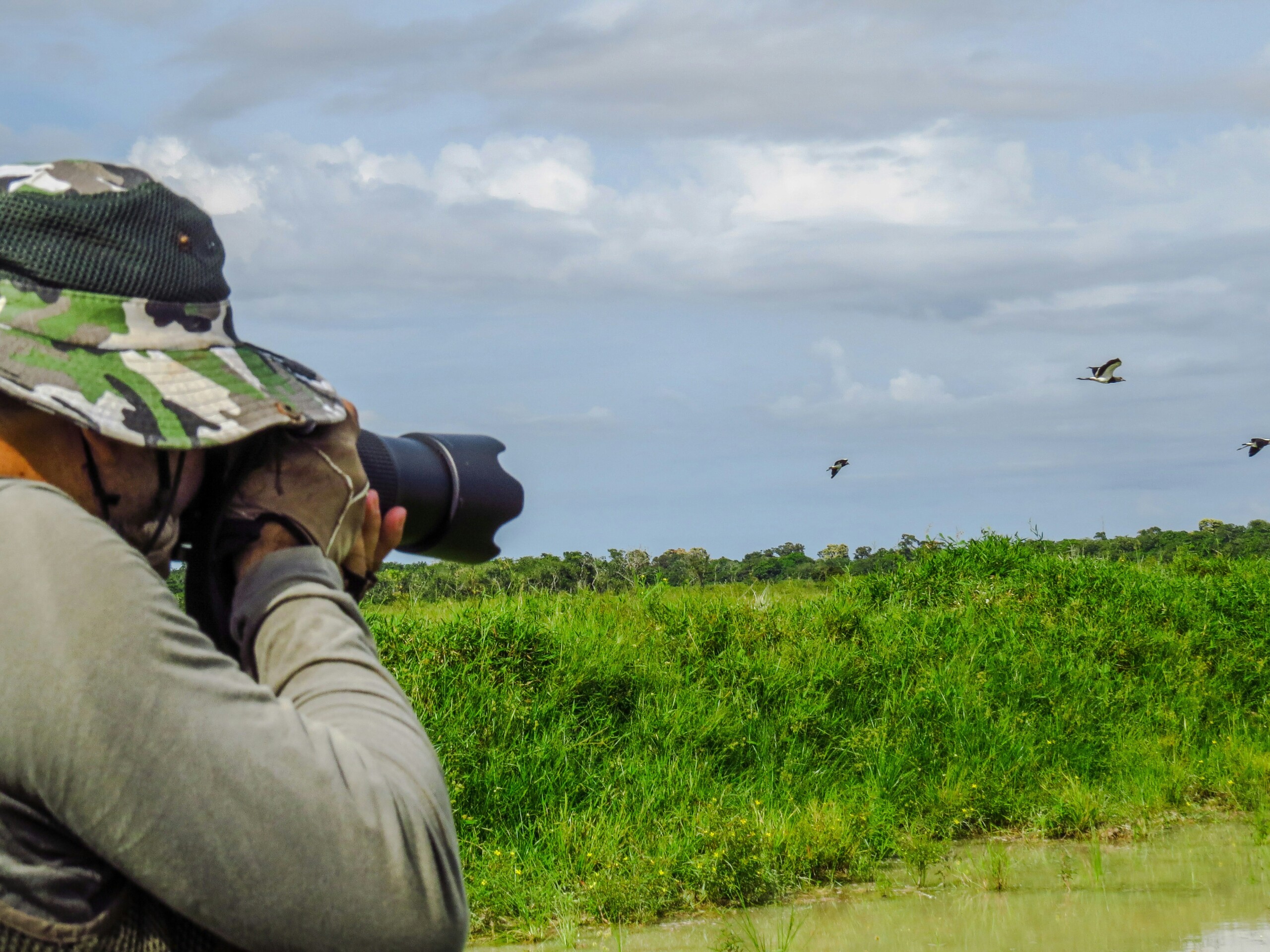 man in gray jacket and black pants taking photo of green grass field during daytime