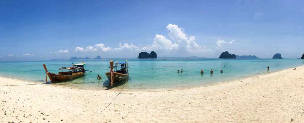 people on beach beside two brown boats during daytime